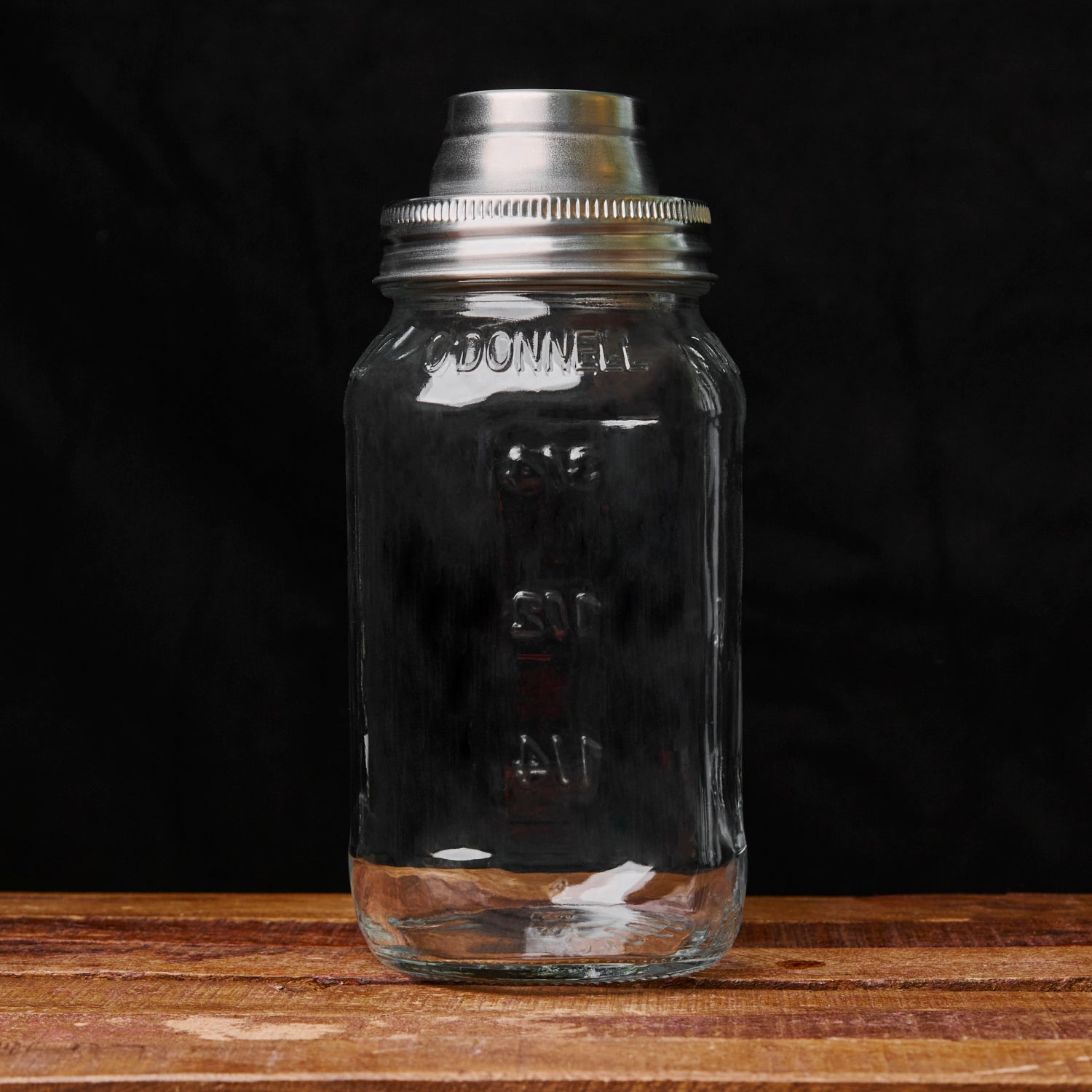 O'Donnell Shakerdeckel auf Mason Jar auf Holztisch vor dunklem Hintergrund