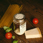 Mason Jar mit Käsereibe-Aufsatz neben Käse, Tomaten und Spaghetti auf Holztisch