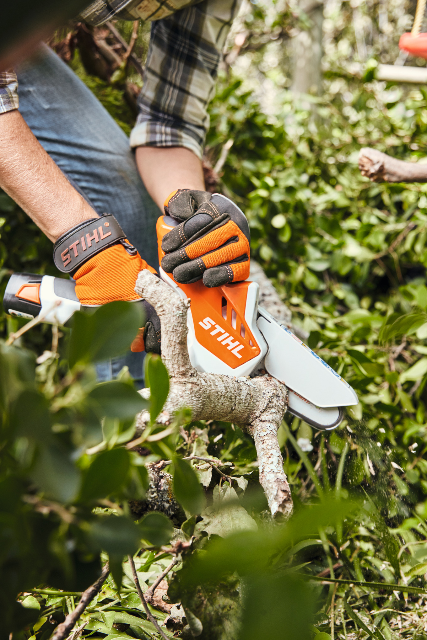 Person schneidet Ast mit Stihl GTA 26 Akku-Gehölzschneider in grüner Gartenlandschaft