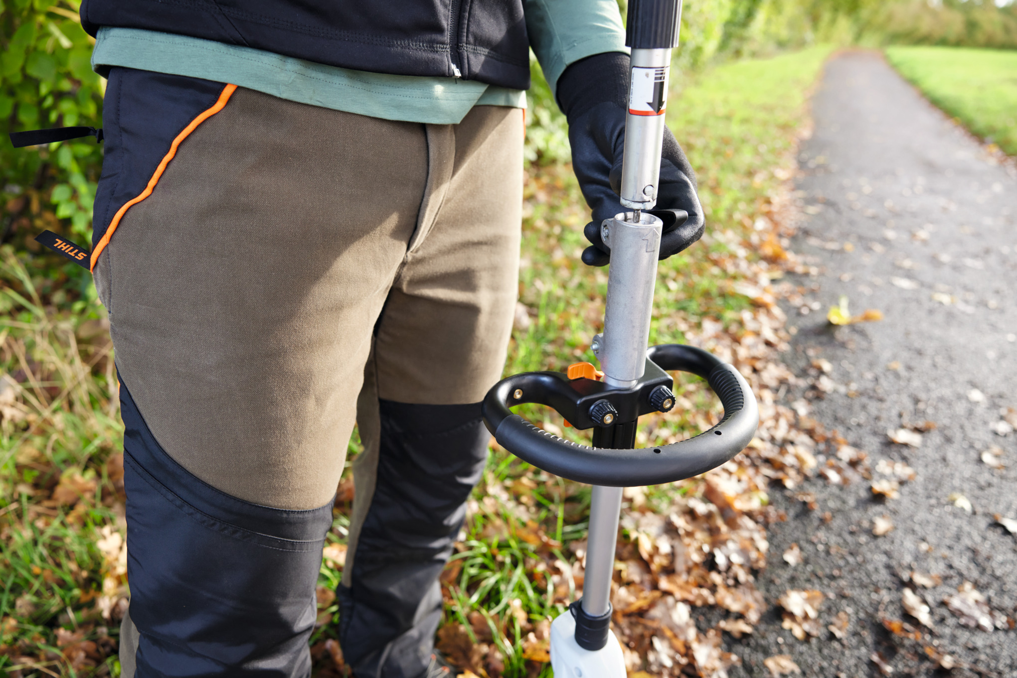 Person bedient Stihl KMA 120 R Akku-KombiMotor auf einem Waldweg