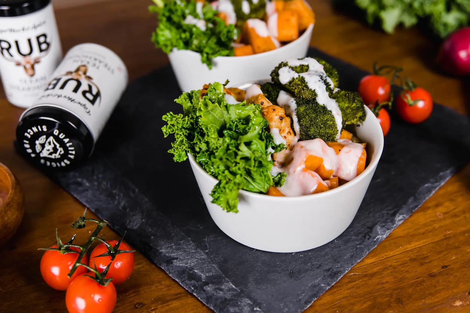 Gewürzte Mahlzeit in weißen Schalen mit Cape Herb Rub Gewürzstreuer und frischen Tomaten
