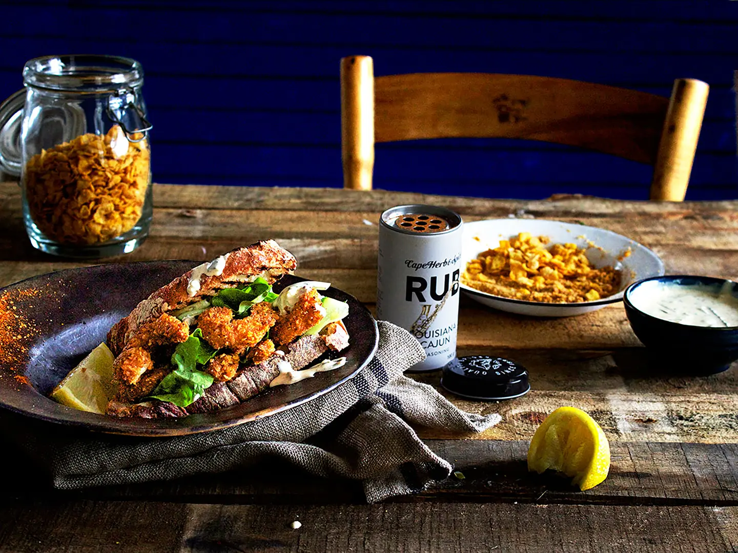 Rustikaler Holztisch mit Cape Herb Rub Louisiana Cajun Gewürz und knusprigem Hähnchengericht
