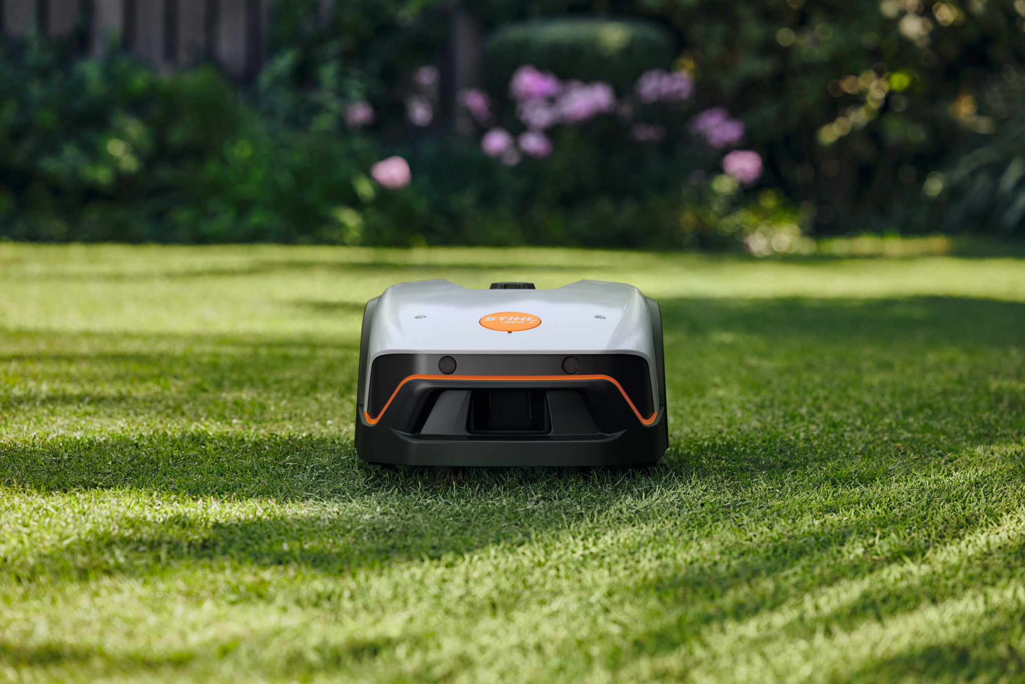 STIHL iMOW 4 Mähroboter mäht autonom in einem grünen Garten