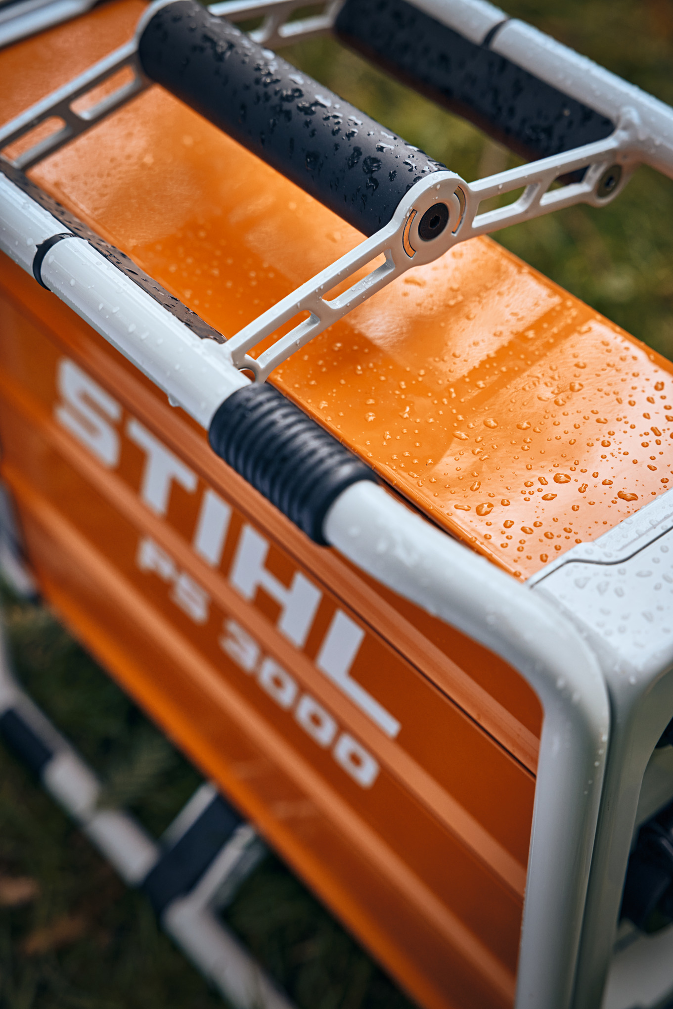 Nahaufnahme eines mobilen Stromgenerators STIHL PS 3000 mit Wassertropfen auf orangefarbenem Gehäuse